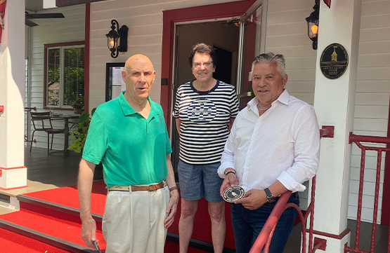 Tom Quick representative receiving Tom Hoff Stewardship Medallions in front of the Tom Quick Inn